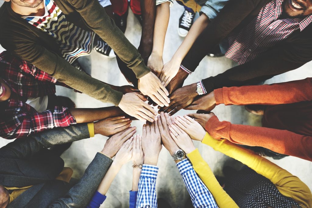 Group of diverse people standing in circle with hands held out and overlapping each other