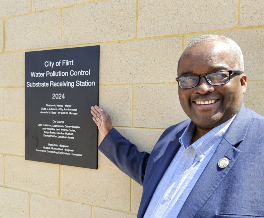 City Administrator Clyde Edwards next to a plaque at the Water Pollution Control Substrate Receiving Station