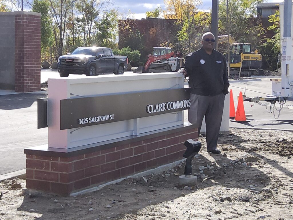 City Administrator Clyde Edwards standing next to a sign in front of Clark Commons