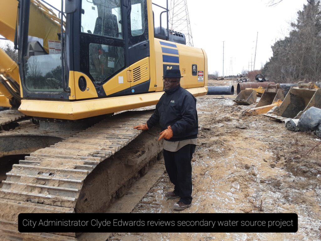 Reviewing construction operations: Clyde Edwards standing next to construction equipment at a construction site.