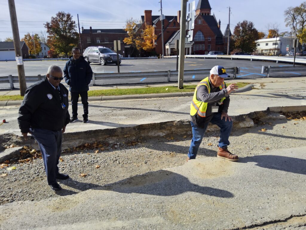 Clyde Edwards and City engineers standing in a portion of dug up roadway inspecting the work.
