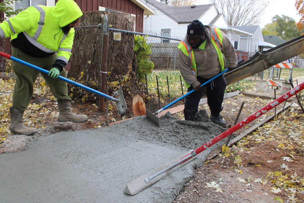 A City Street Maintenance crew pouring a new segment of sidewalk on a neighborhood street