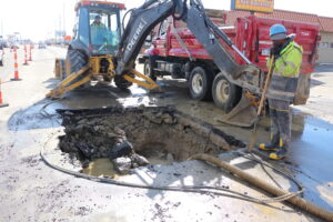 City workers operate machinery to fix a water main break on Dort Hwy.