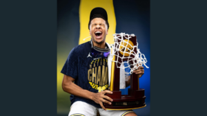 University of Michigan basketball player Trey McKenney poses with the NCAA Men's Basketball Championship trophy.