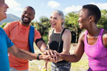 Mature adults in a huddle with their hands in the middle
