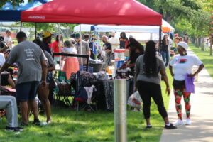 A crowd of people standing under and around tents set up on the grounds of the Flint Cultural Center.