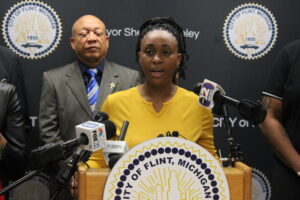 Division of Health Strategies and Advancement Director Shebra Ward addresses the media during a press conference at Flint City Hall with Mayor Sheldon Neeley standing behind her right shoulder.