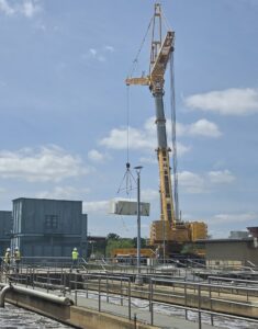 A very large crane lowering one of two new electrical control room units into place at the Flint Wastewater Treatment Plant.